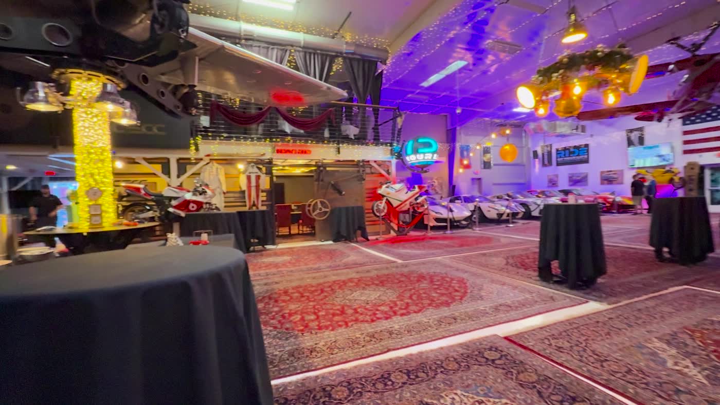 Evening event set up on the main floor at the Carolina Exotic Car Club, cars and tables under the lights